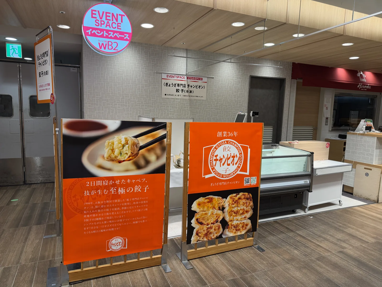 イベントスペースに設営された、ぎょうざ専門店チャンピオンの売り場。オレンジ色の大きなのぼり2枚と、冷凍のショーケースが並んでいる